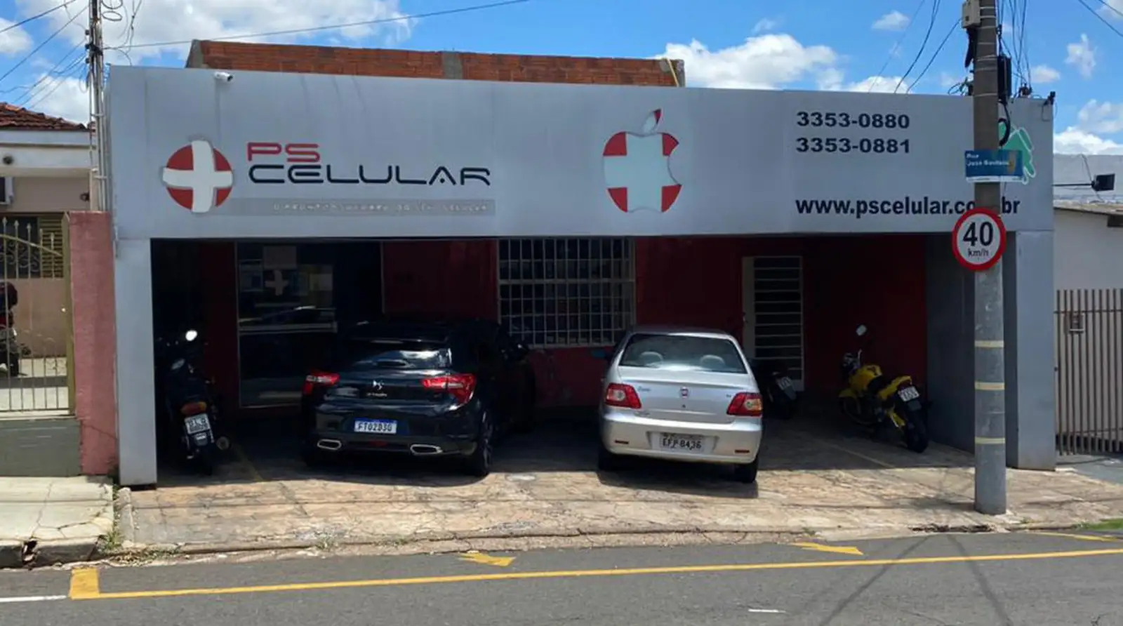 Fachada da PS Celular na Rua José Bonifácio: a placa com a cruz vermelha, os telefones 3353-0880 e 3353-0881 e o estacionamento coberto.